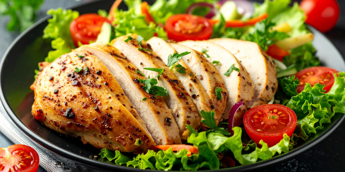 Sliced grilled chicken breast on a bed of lettuce and tomatoes